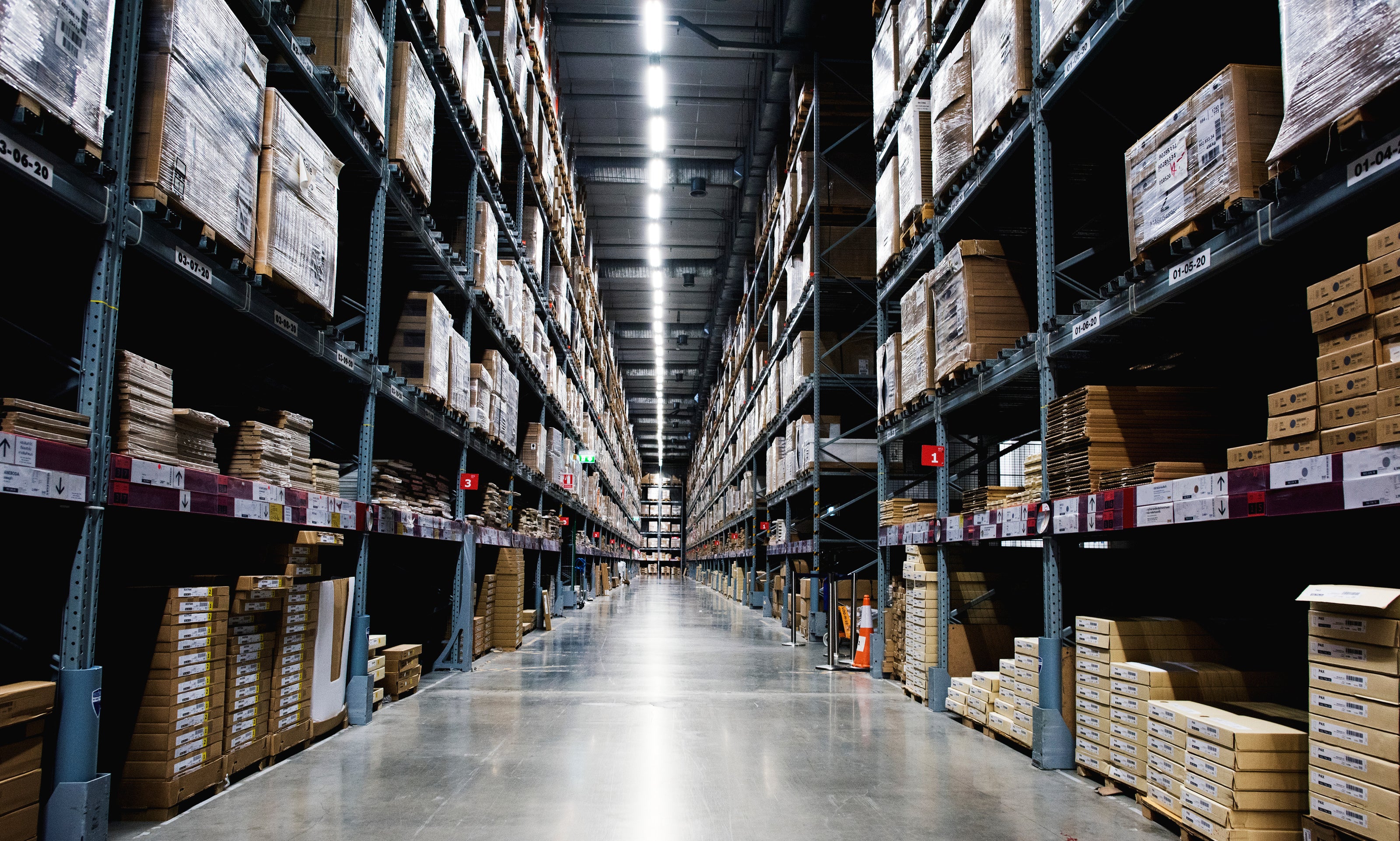 Long aisle in a warehouse with high shelves filled with boxes
