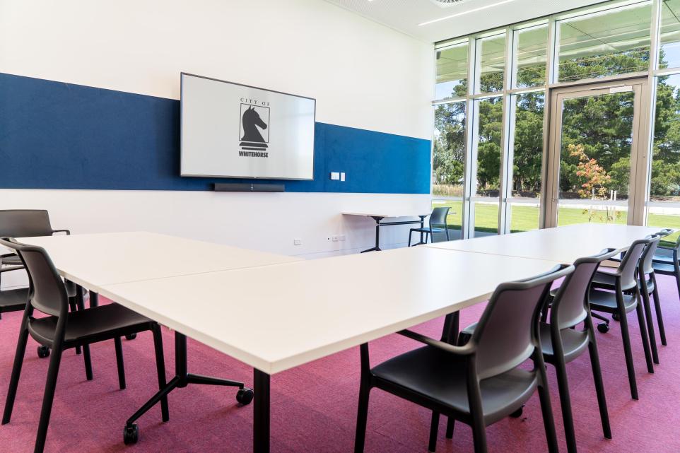 Modern conference room with a large table, chairs, and a screen displaying a logo.