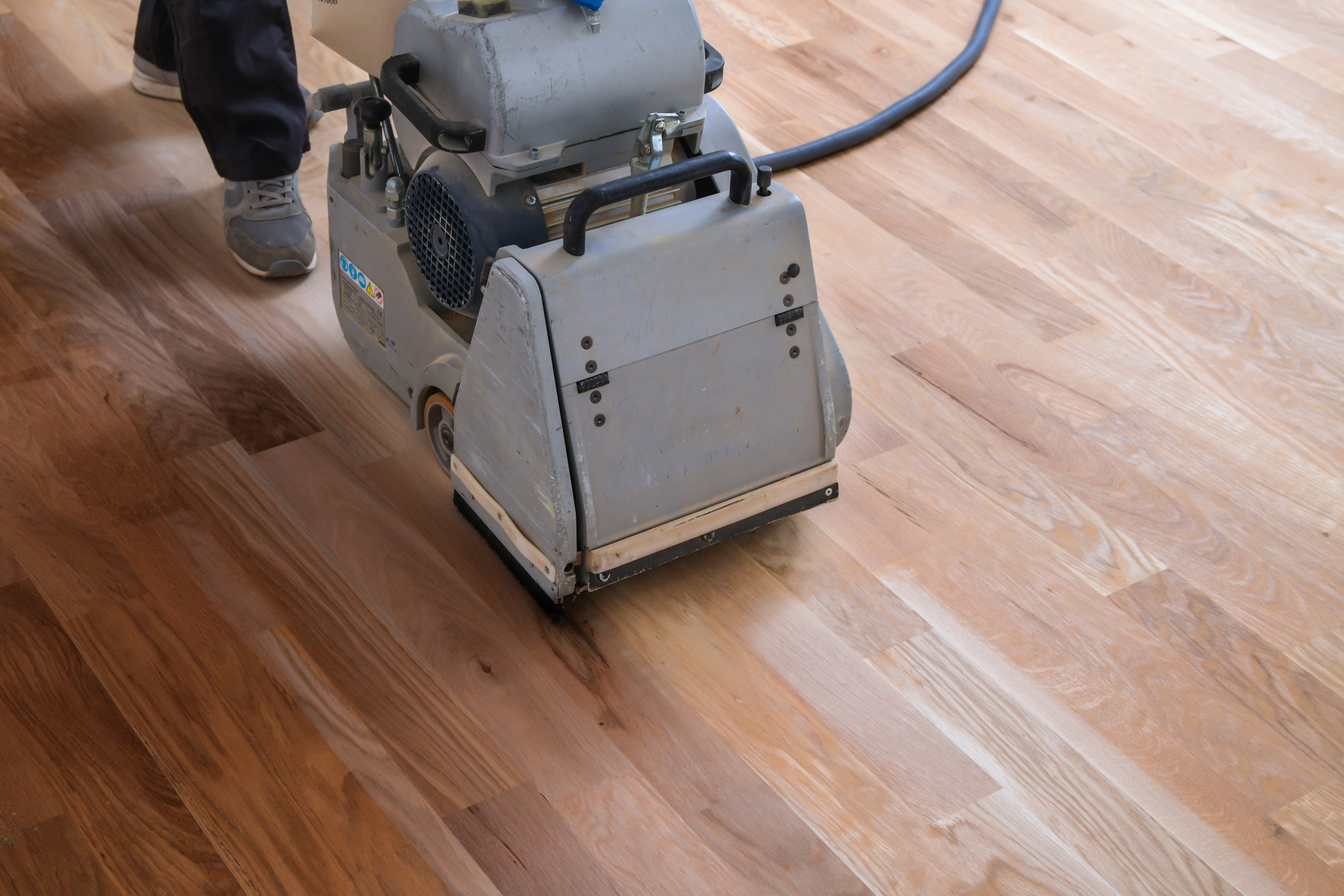 Person using a floor polisher on a wooden floor